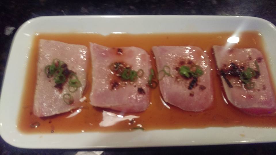 A white plate topped with meat and sauce on a table