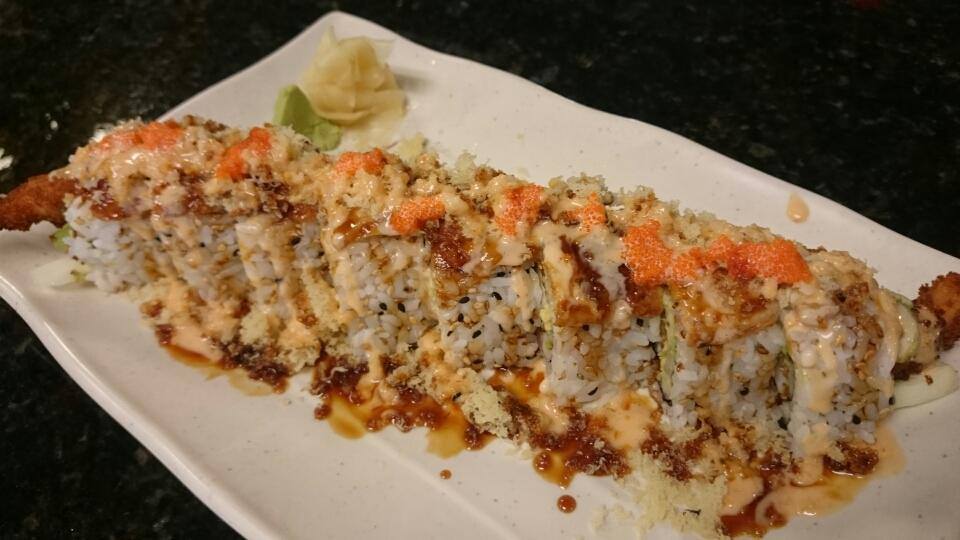 A long white plate topped with sushi and sauce on a table.