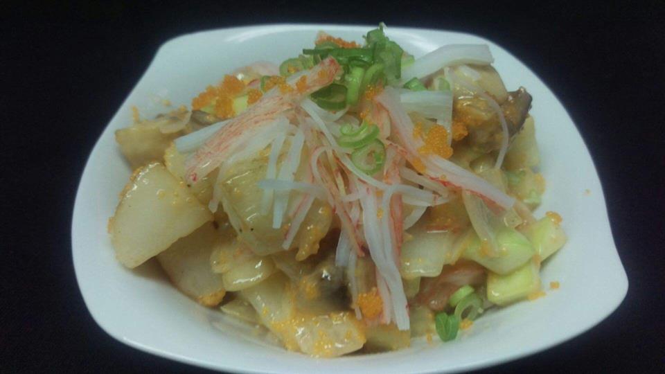A white bowl filled with vegetables and meat on a black background.