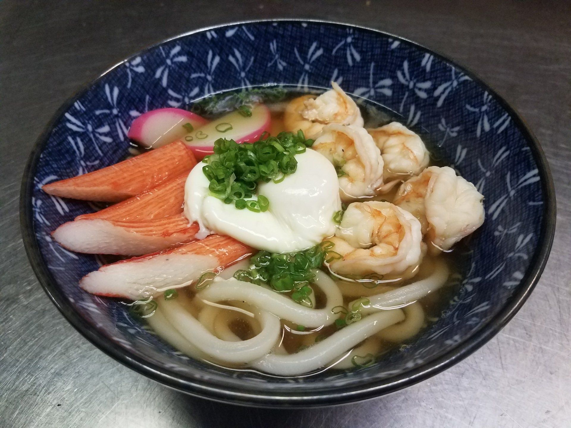 A bowl of udon soup with shrimp and crab sticks