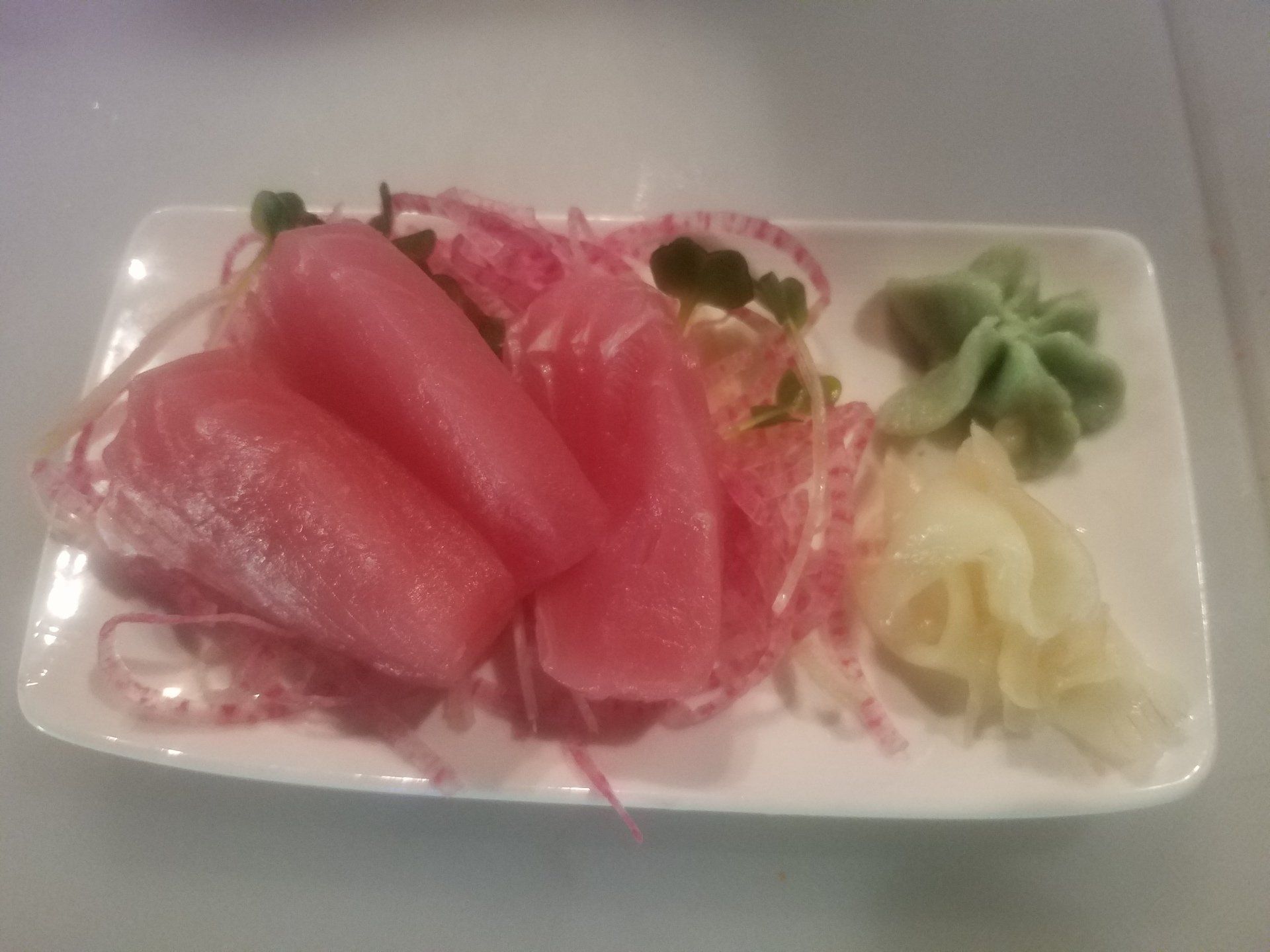 A white plate topped with sliced fish and vegetables on a table.