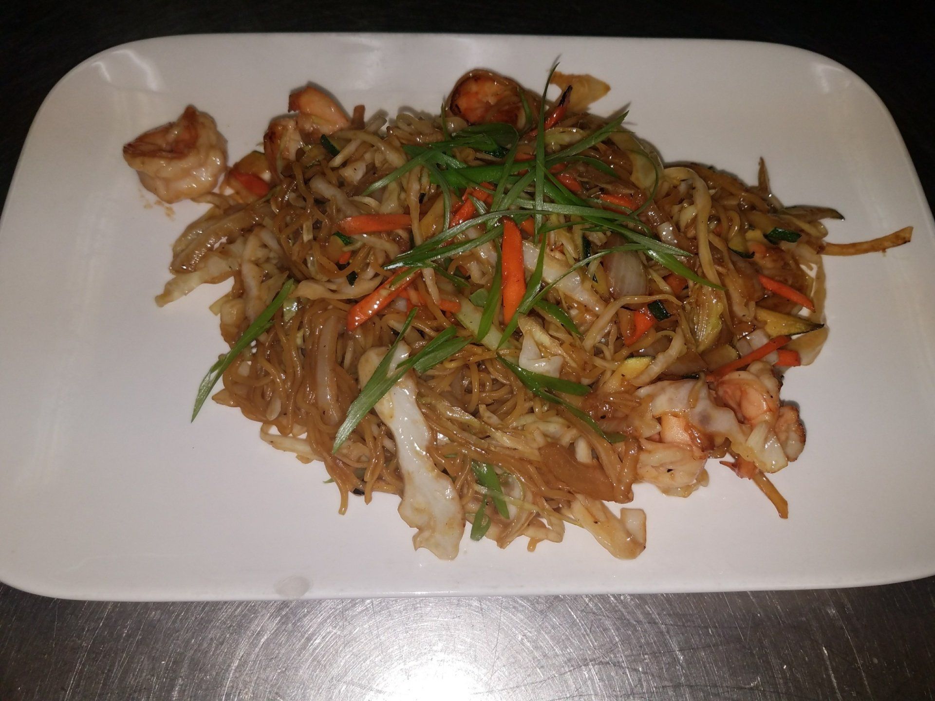 A white plate topped with noodles and vegetables on a table.