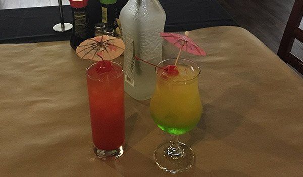 Two drinks with umbrellas on them are sitting on a table.