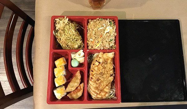 A tray of food is sitting on a table next to a chair.