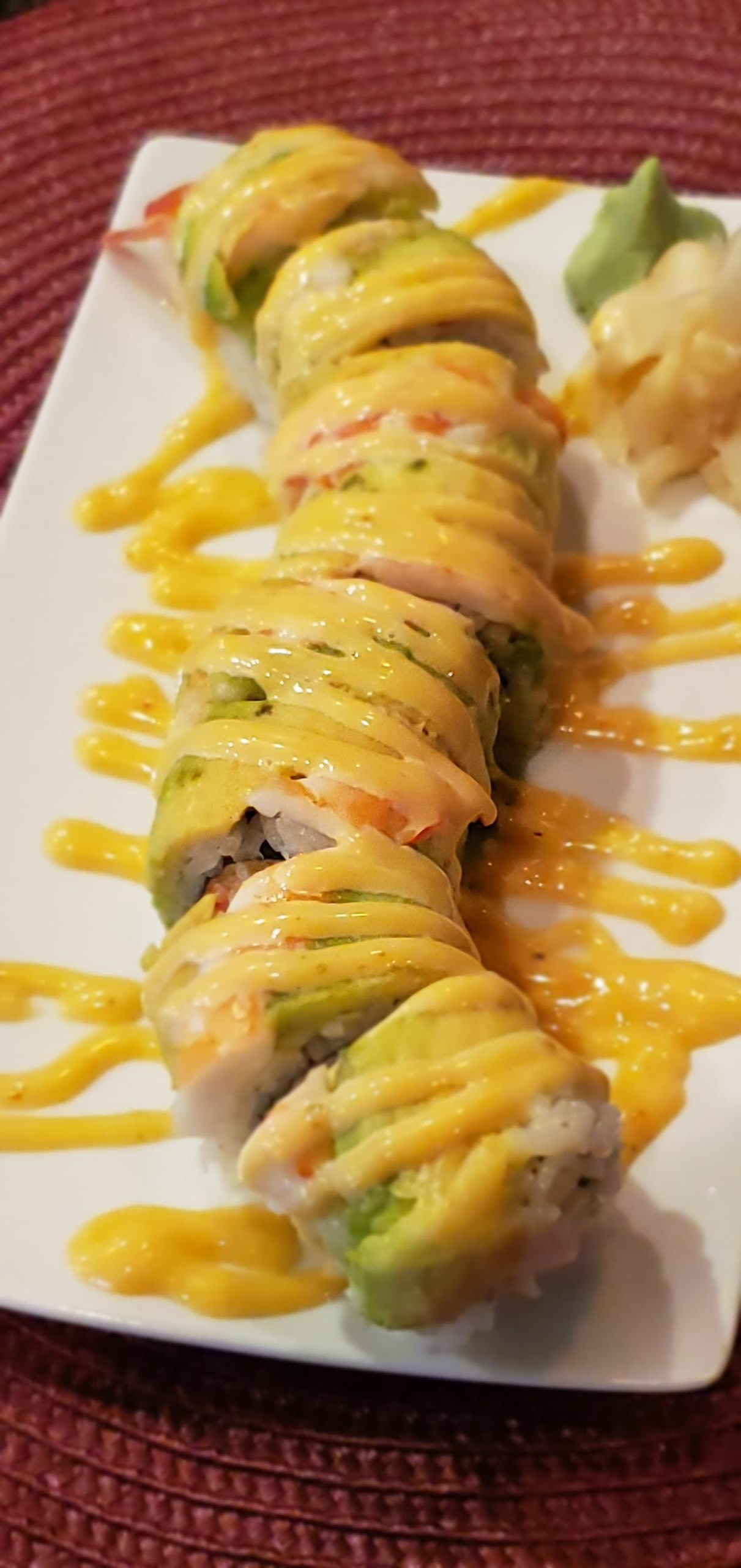 A close up of a sushi roll on a white plate on a table.