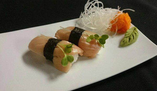 A white plate topped with sushi and vegetables on a table