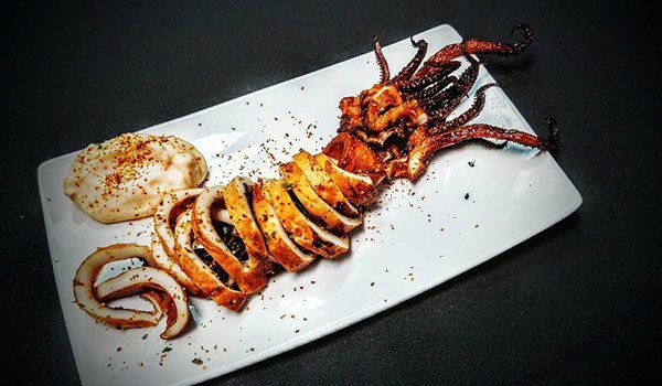 A large squid is sitting on a white plate on a table.