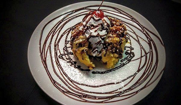 A white plate topped with a dessert with a cherry on top.