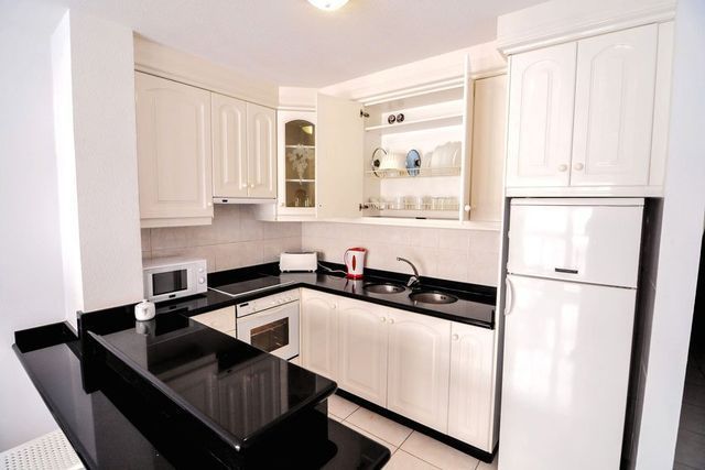 A kitchen with white cabinets and black counter tops