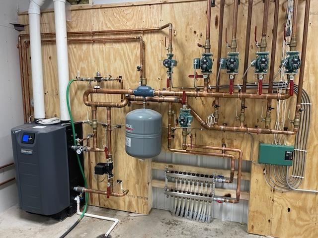 A room with a boiler and a lot of pipes on the wall.