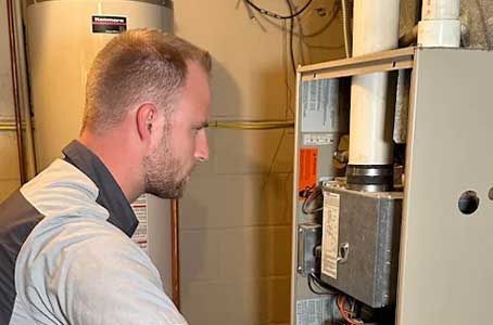 Person inspecting a wall-mounted furnace in a utility room