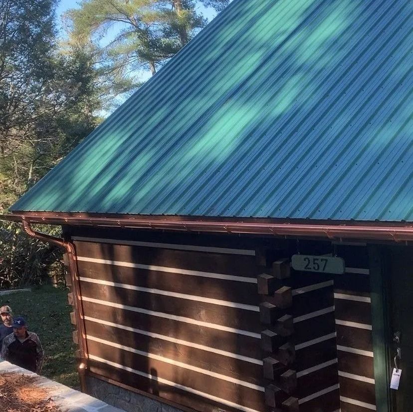 Cabin with green roof and brown log siding; sign says 