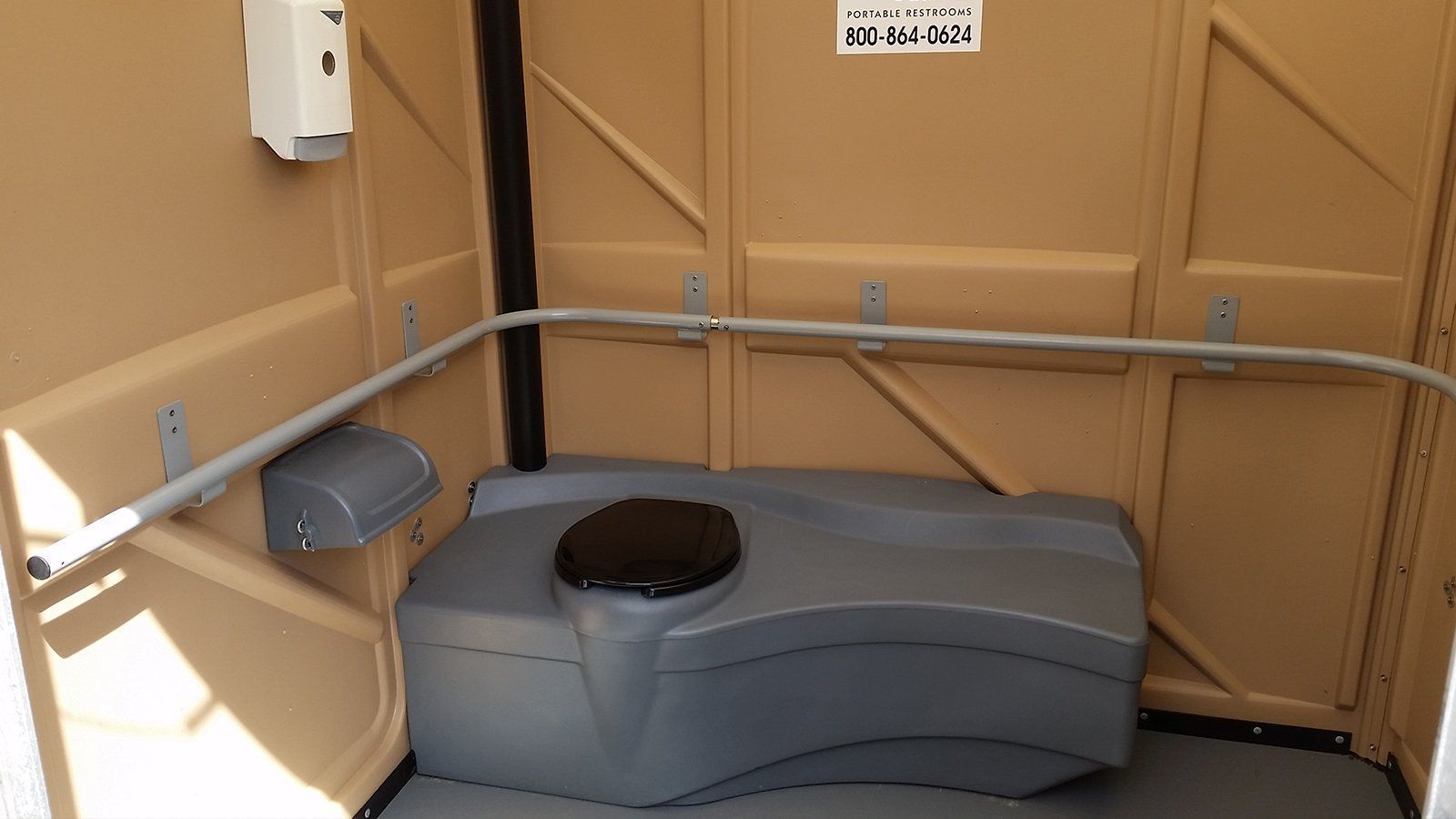 A portable toilet with a soap dispenser on the wall