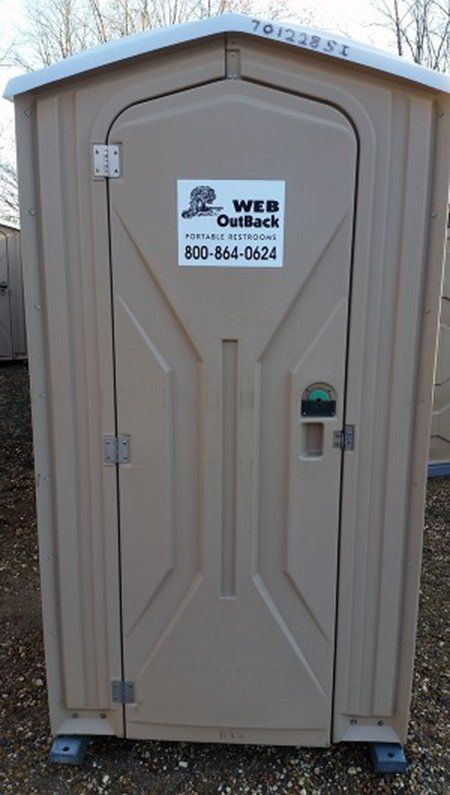 A small brown portable toilet with a sticker on the door that says wes quick.