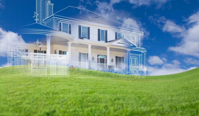 House with blueprint overlay on a grassy hill against a blue sky with clouds.