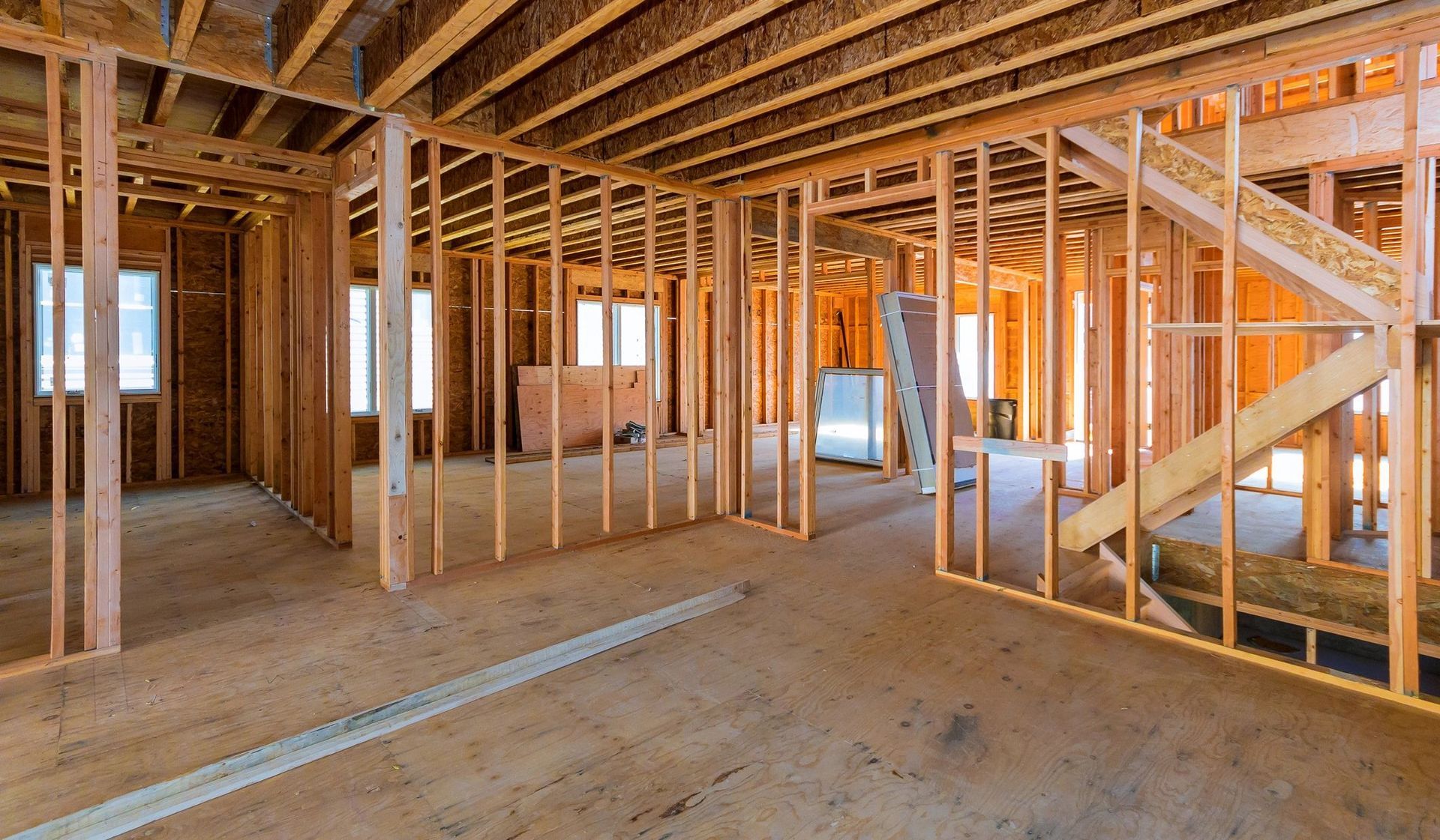 Interior of a building under construction, showing wooden framing and a staircase.