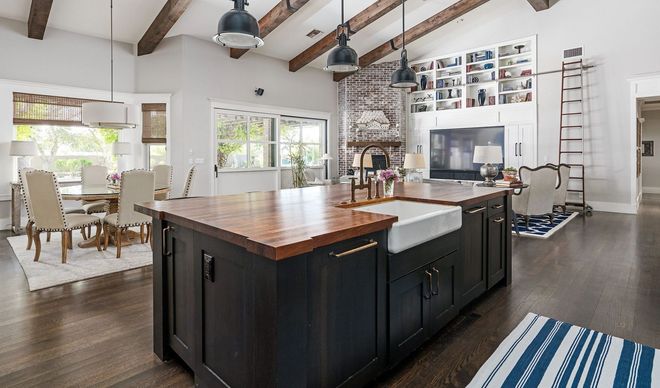Spacious kitchen with island, farmhouse sink, wood countertops, and white cabinets.