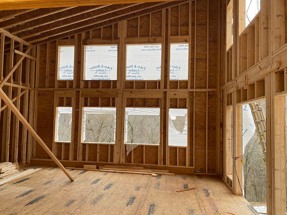 Interior of a building under construction; wooden framing with window openings.