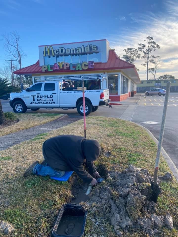A person is digging near a McDonald's Playplace, with a Tru-Flo truck parked nearby.