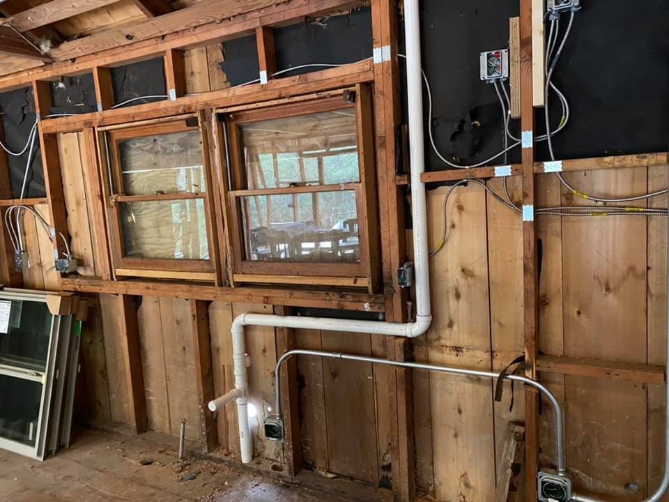 Interior view of a building with exposed framing, two windows, and electrical wiring.