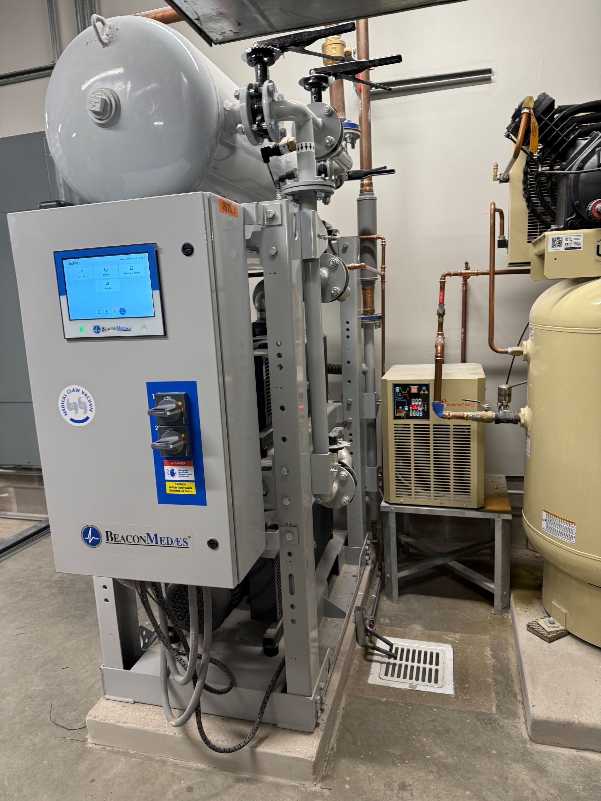 Industrial air compressor system in a utility room. Includes tanks, gauges, and control panel.