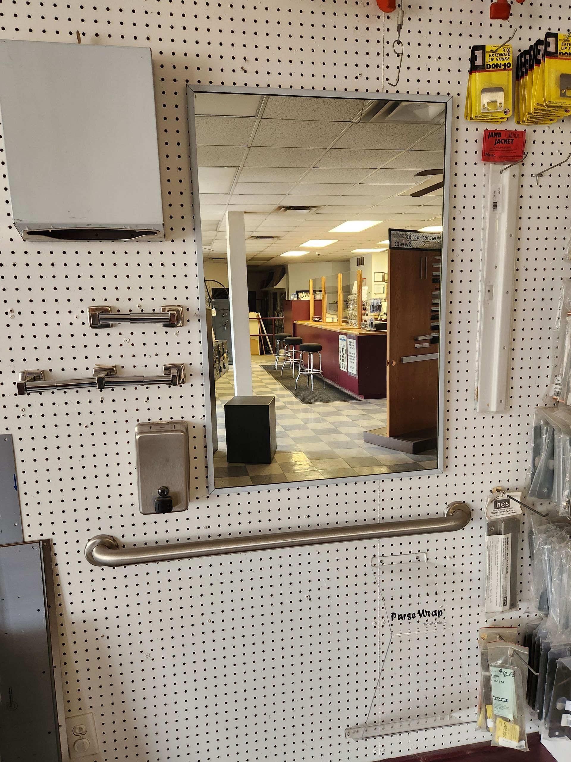 Mirror reflecting a barber shop interior with shelves of items and a grab bar.