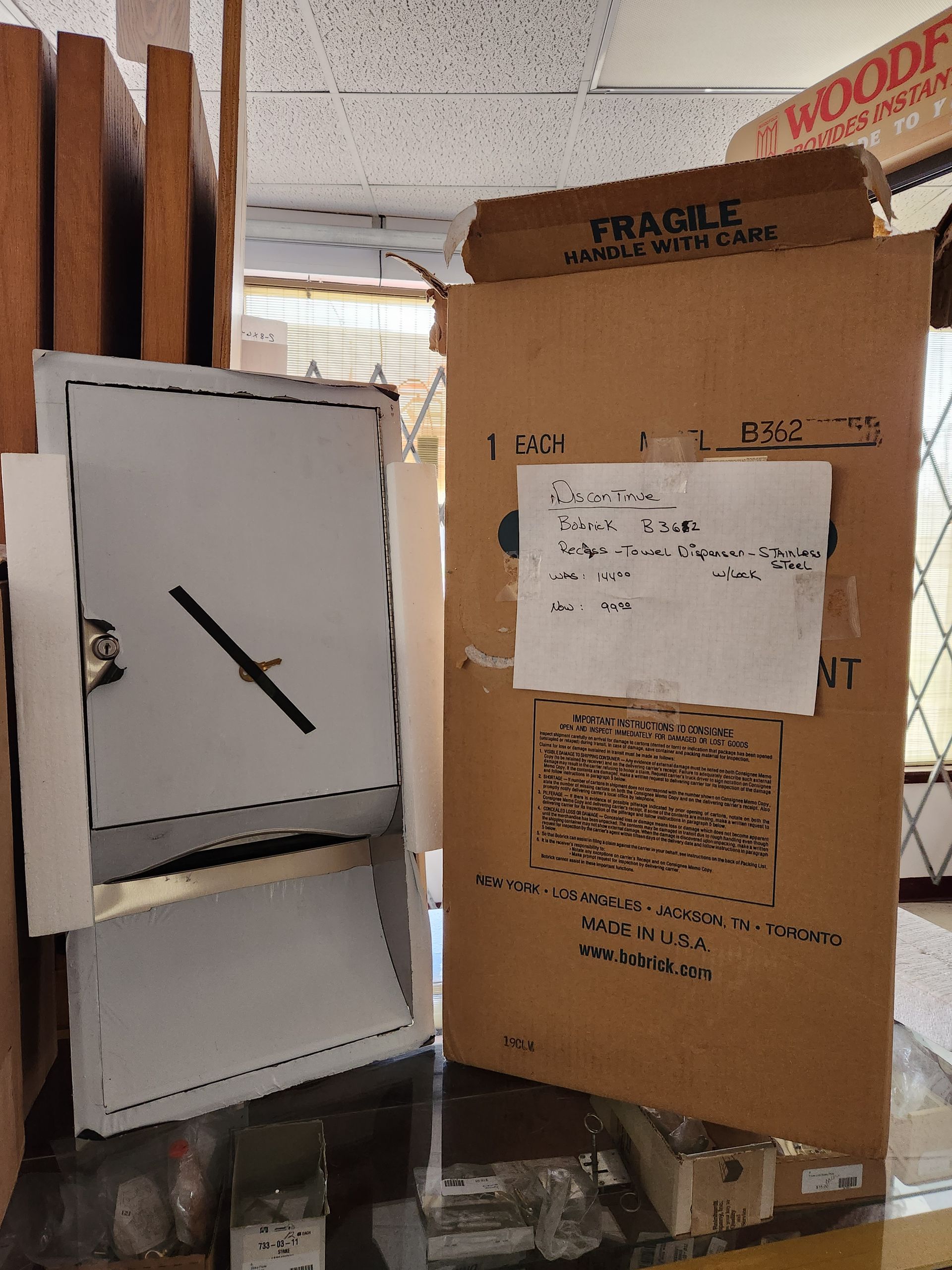 Cardboard boxes and a metal box on a shelf. The large box has a fragile label.