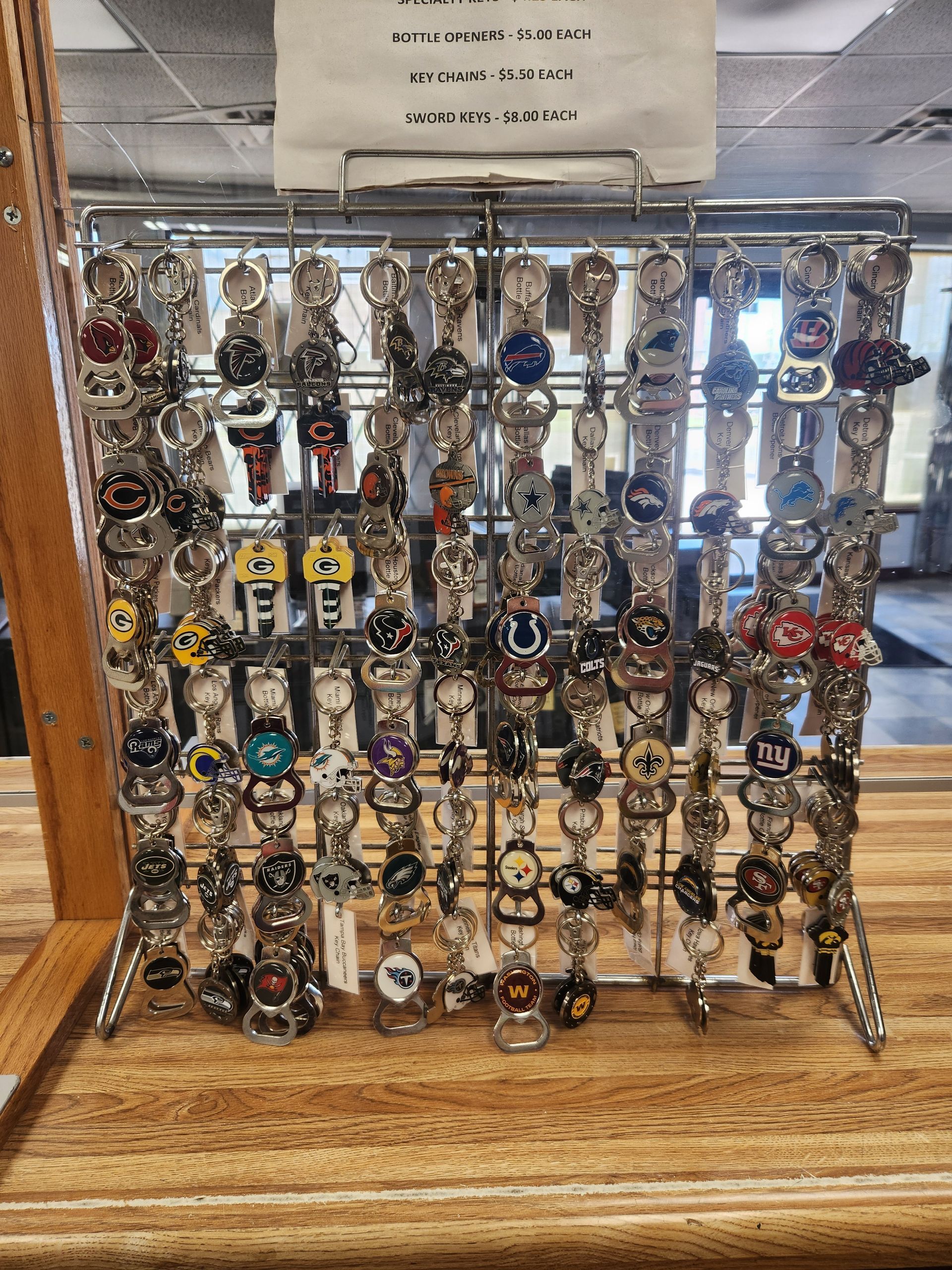 Keychains displayed on a metal rack, variety of designs, set on a wooden table.
