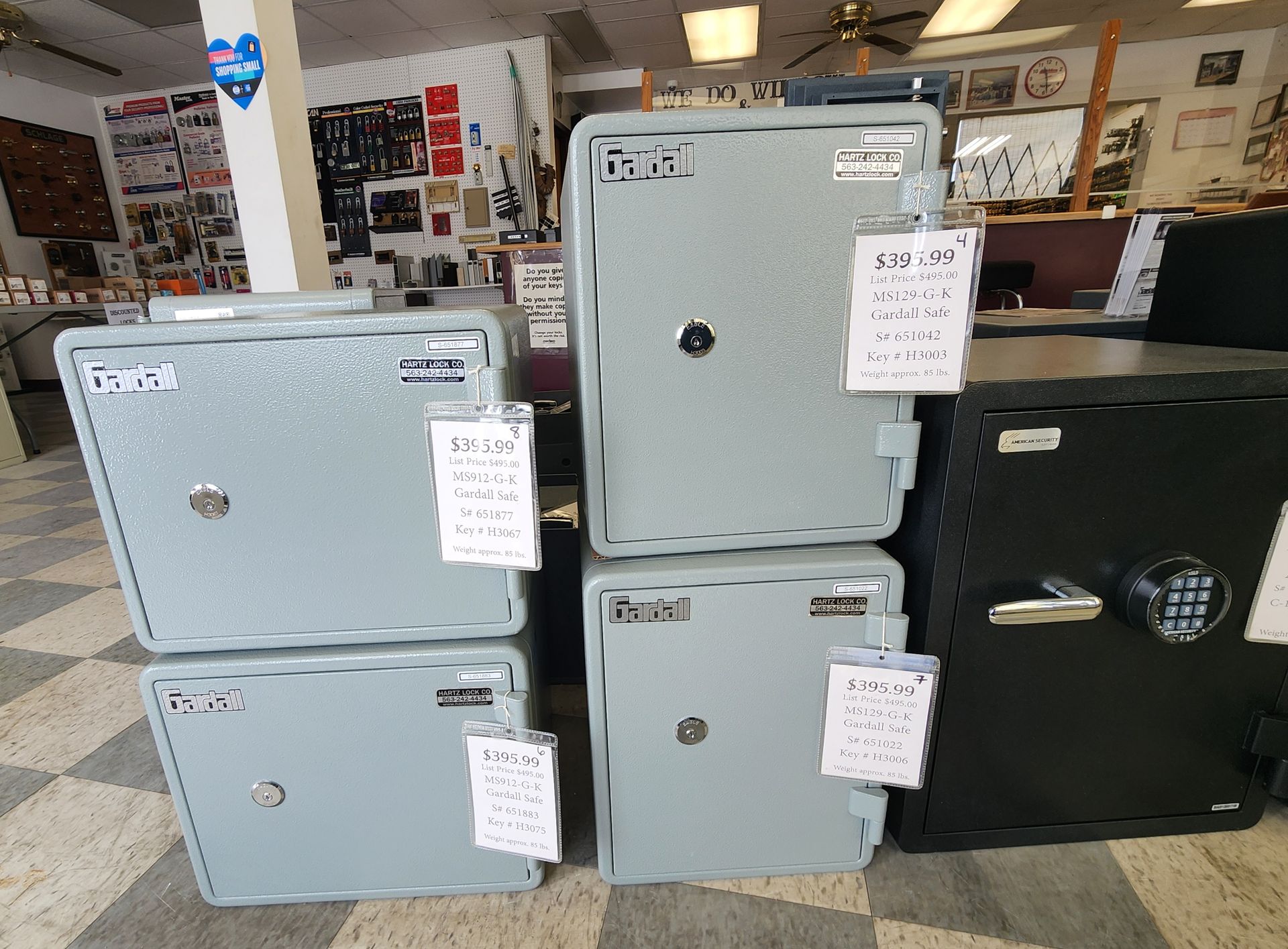 A collection of gray and black safes with price tags on display in a store showroom.