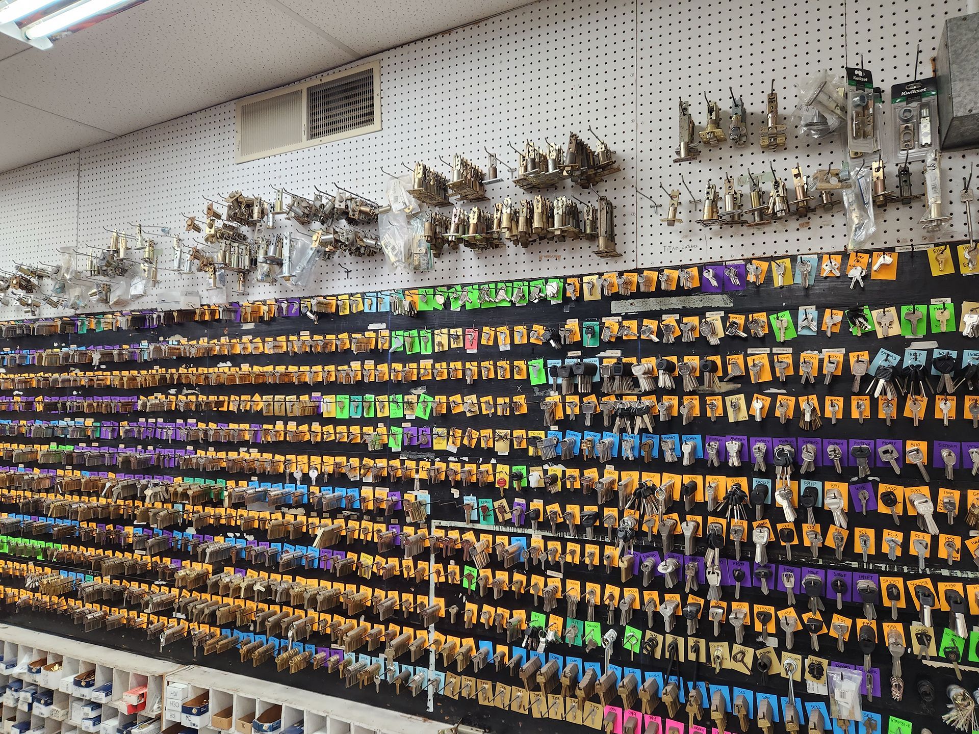 Wall of keys in a hardware store, arranged by color and type.