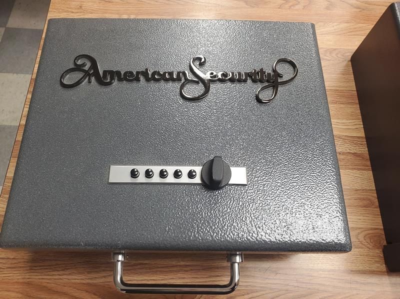 A gray American Security safe with a combination dial and handle.