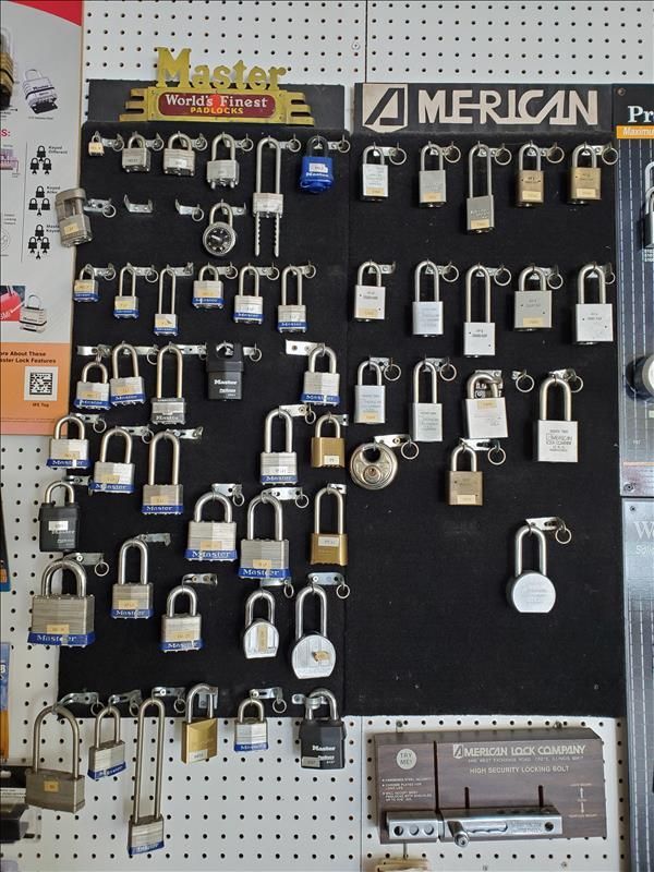 Display of various padlocks on a black pegboard at a store, showcasing different sizes and brands.