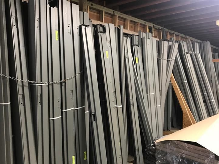 Gray metal door frames leaning against a wall in a storage area.