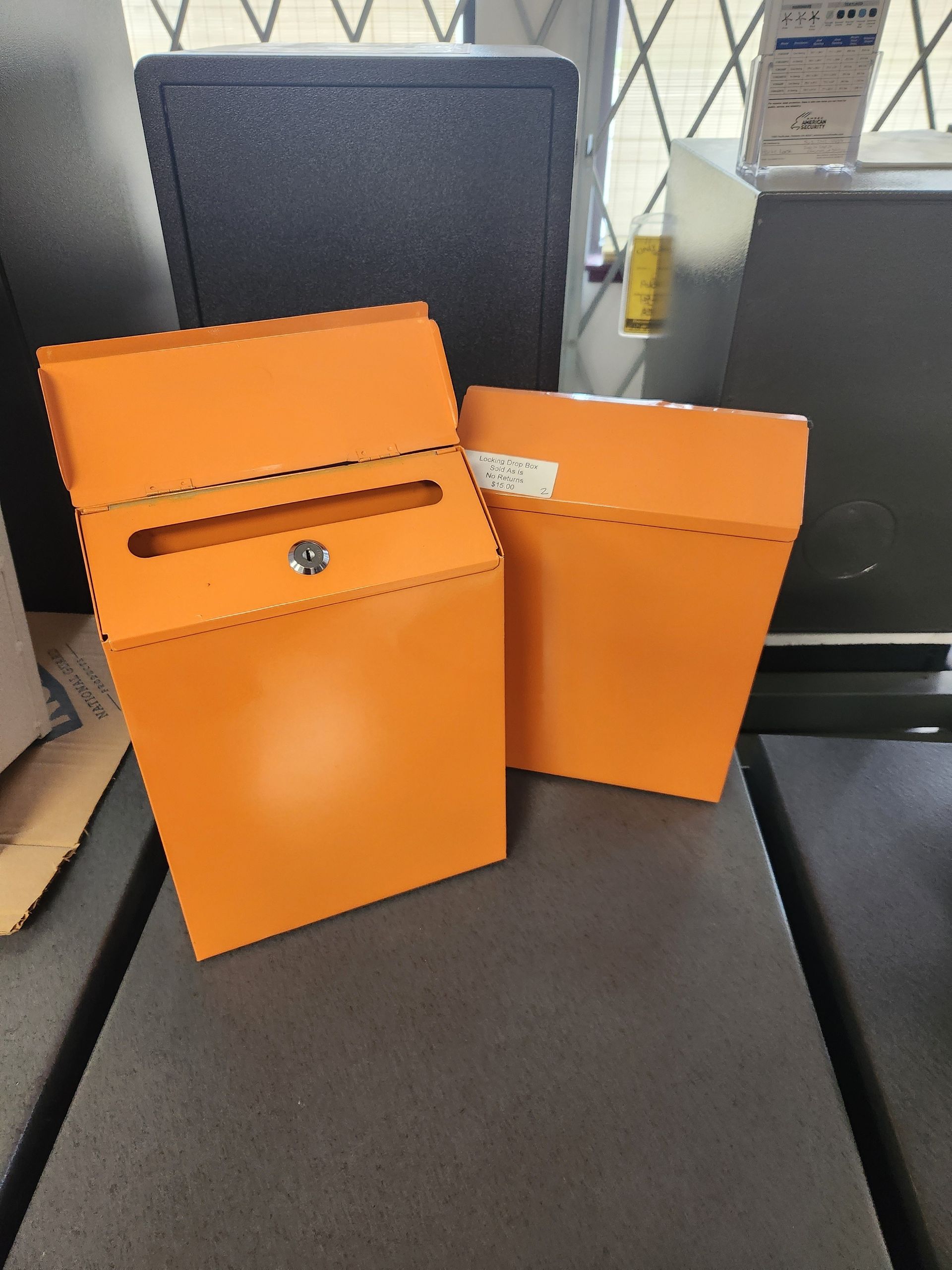 Two orange mailboxes on a dark surface, one open showing keyhole, other closed.