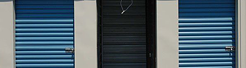 a row of blue and black storage doors on a building .