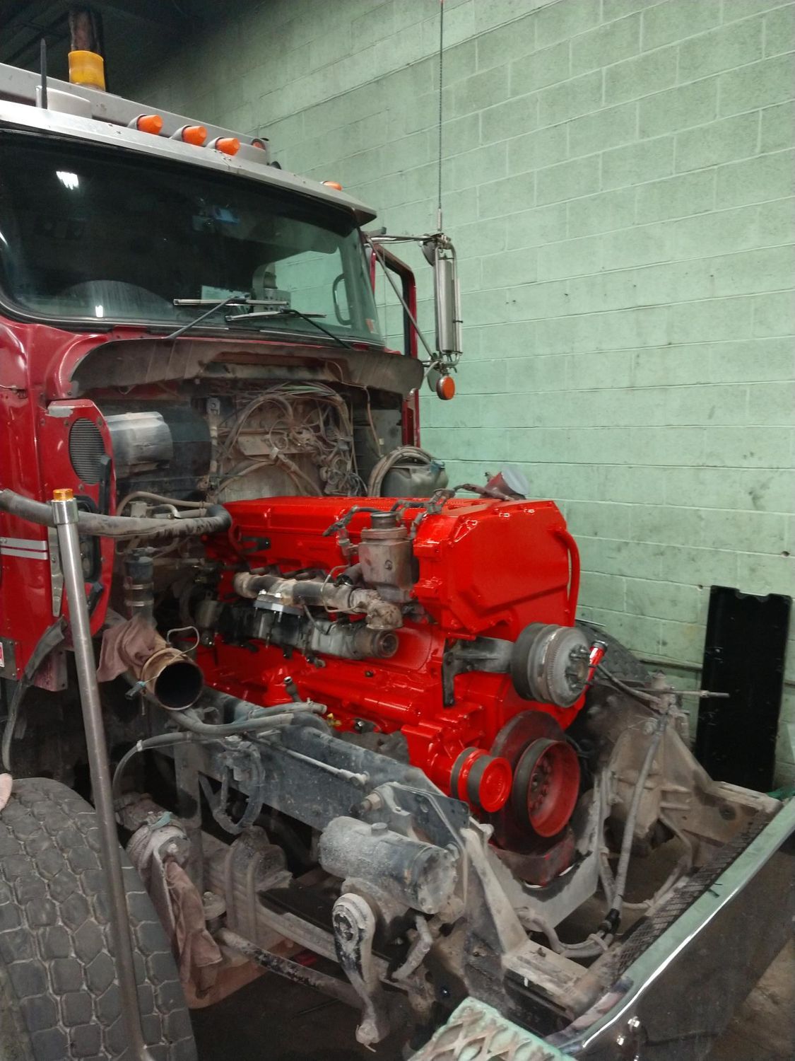 Red truck engine exposed, in a repair shop. The engine is painted red.