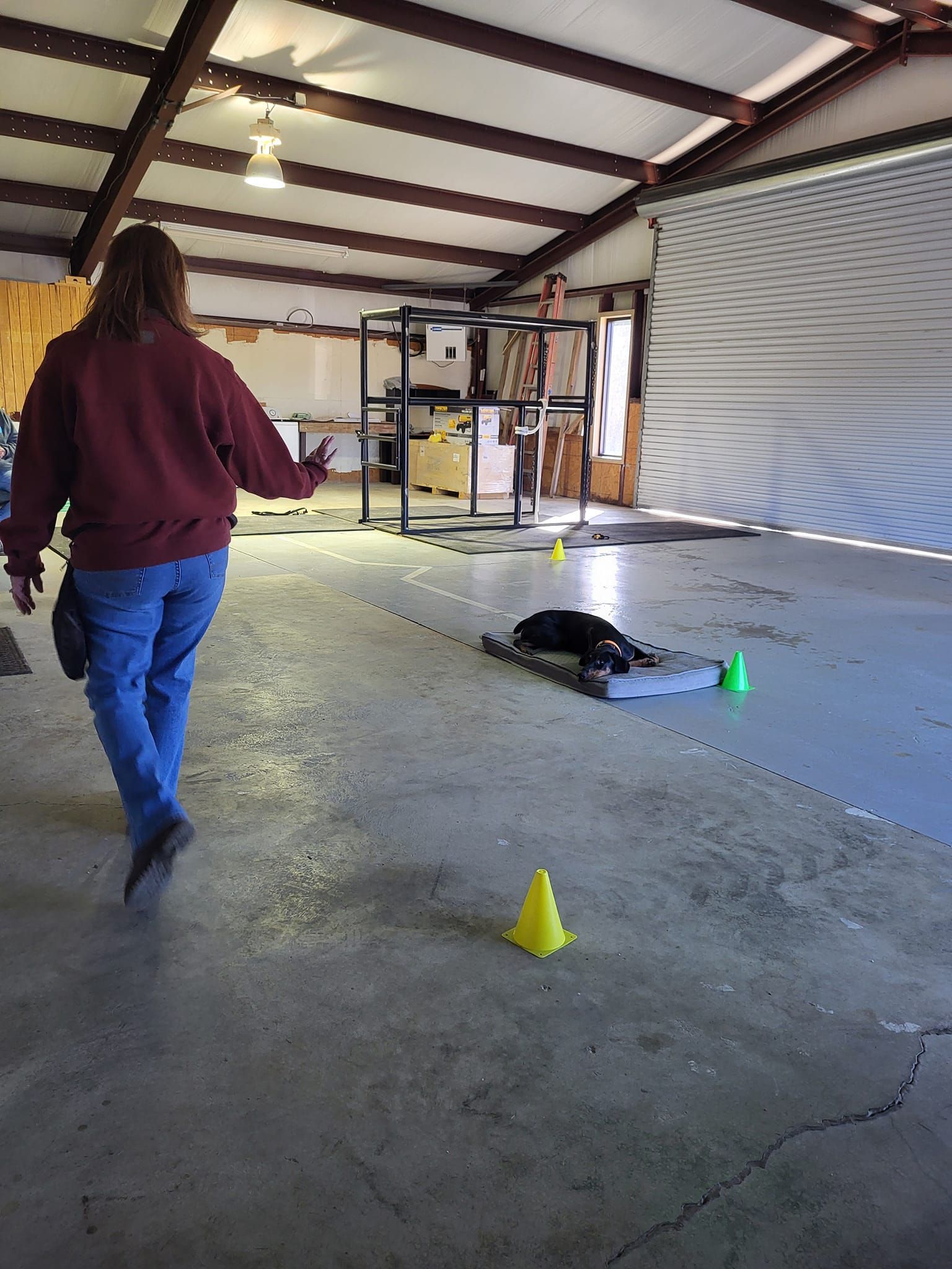 A woman is walking through a garage with cones on the floor