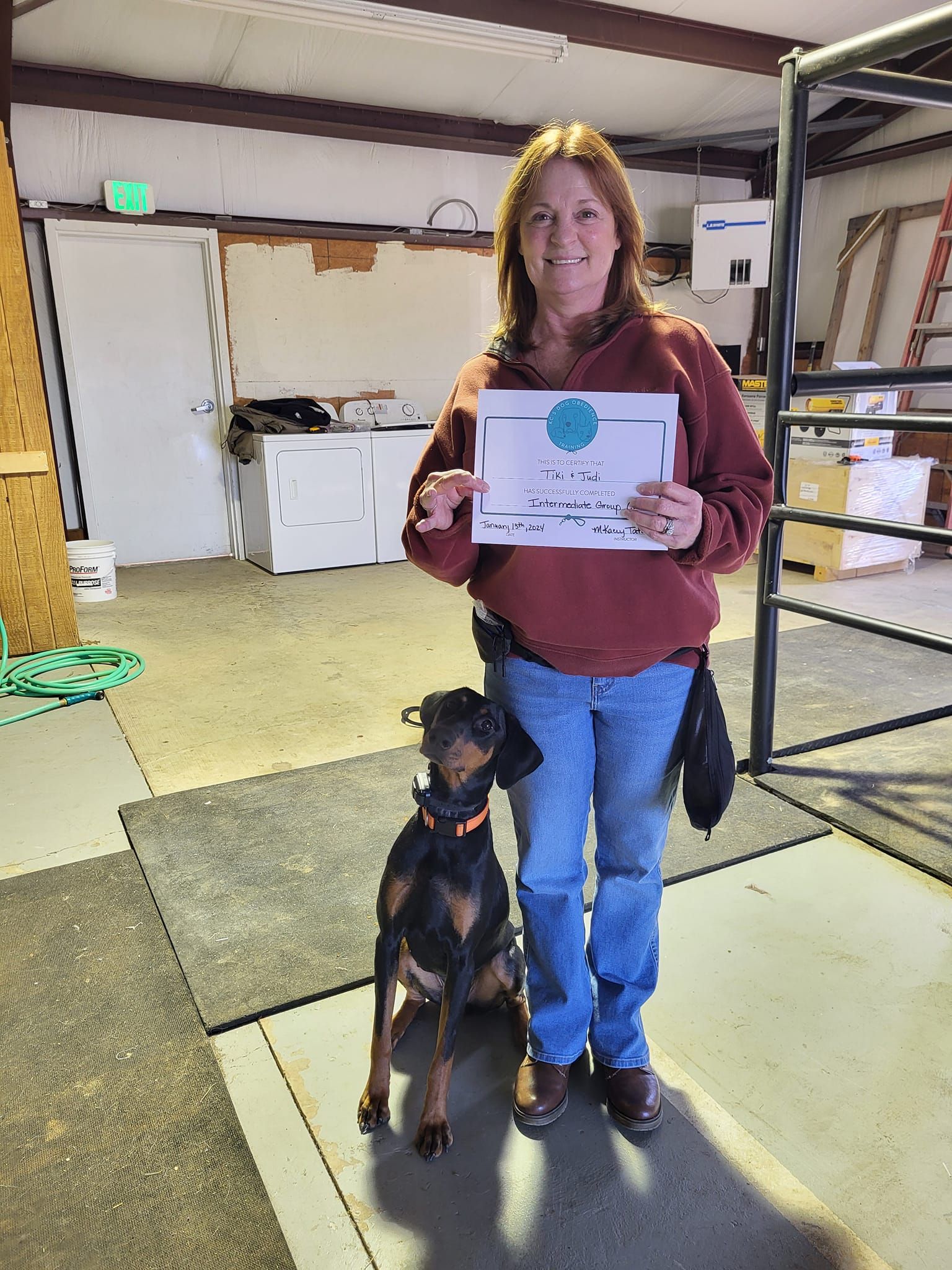 A woman is standing next to a dog and holding a certificate
