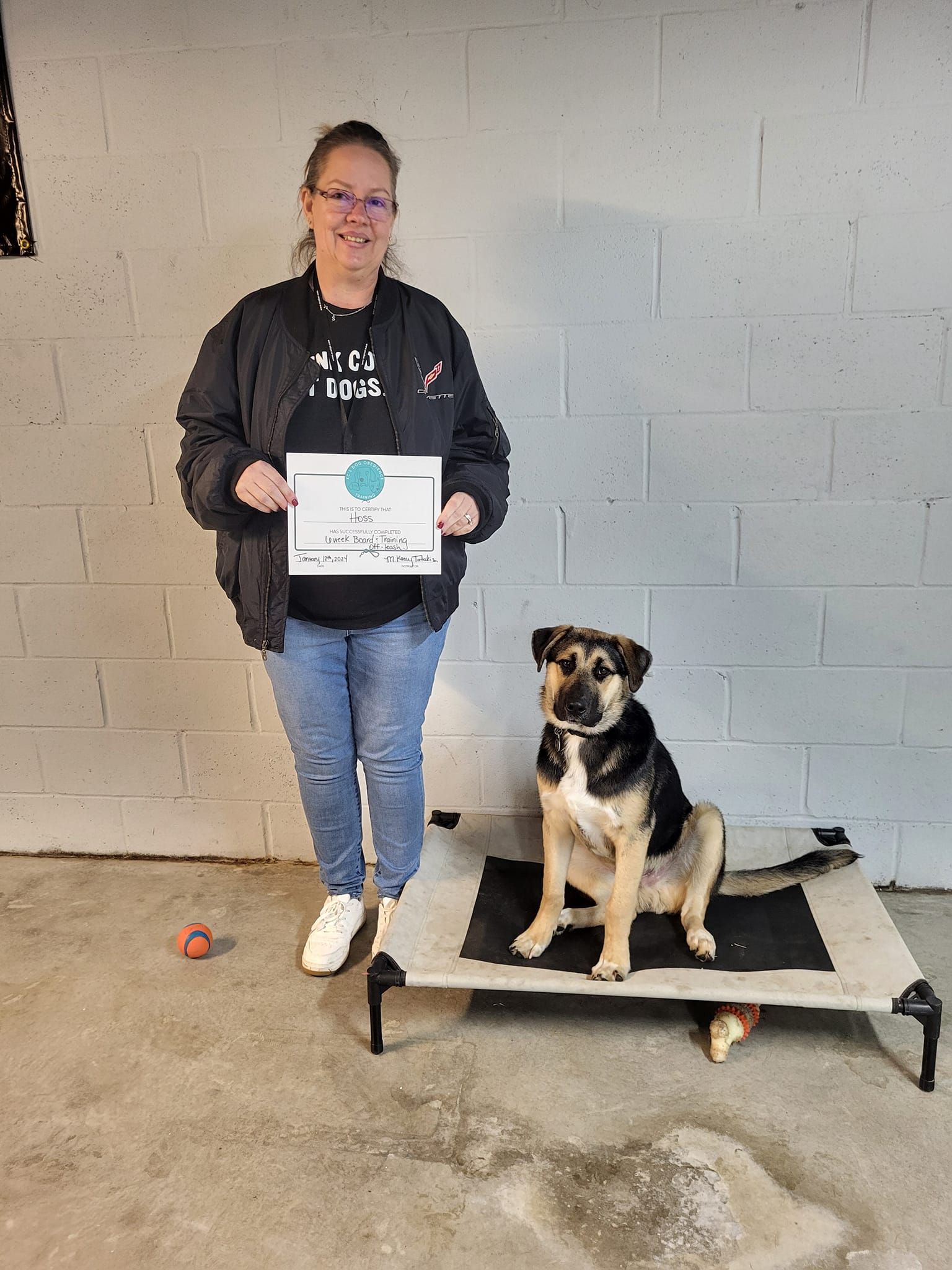 A woman is standing next to a dog on a bed holding a certificate