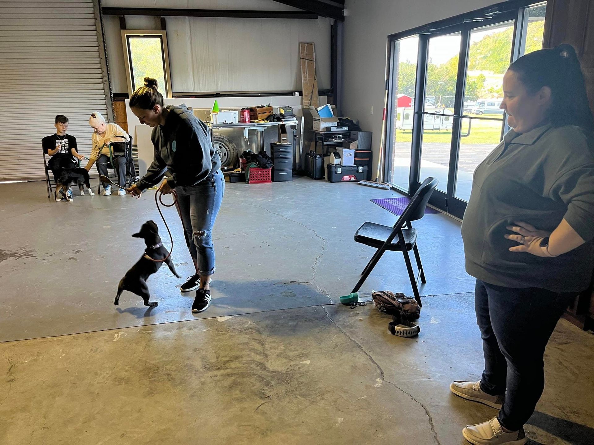 A woman is standing next to a dog on a leash in a room