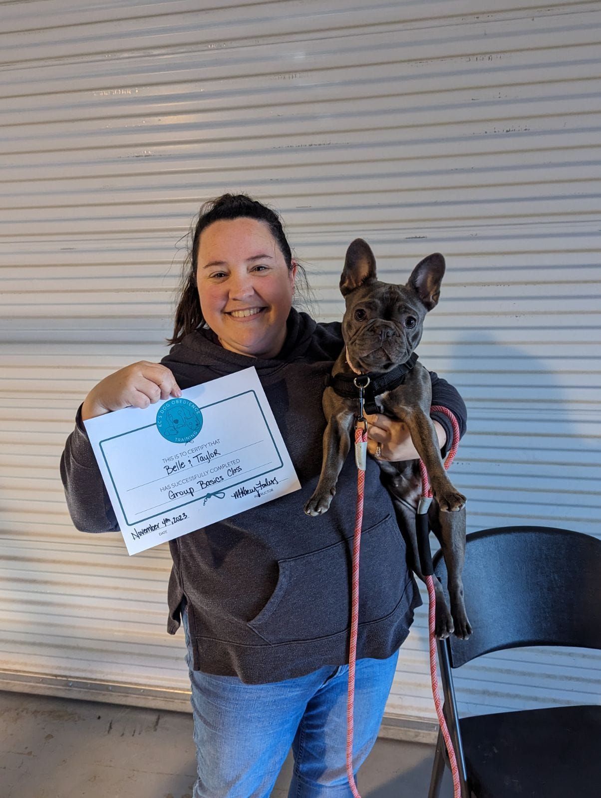 A woman is holding a dog in her arms and holding a certificate
