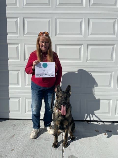 A woman standing next to a dog holding a certificate