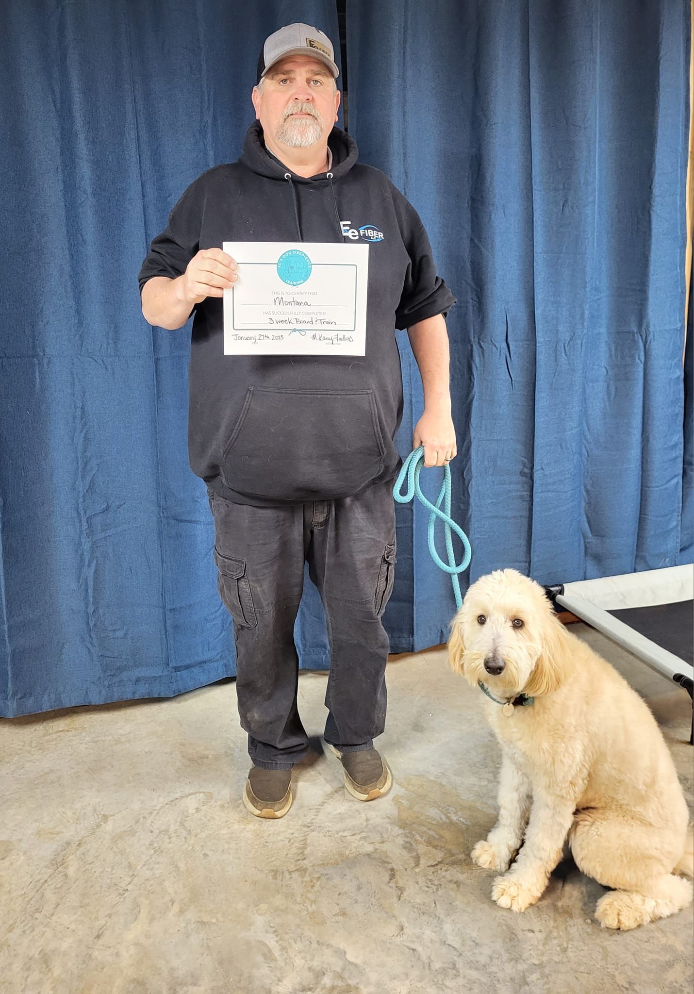 A man is standing next to a dog on a leash and holding a certificate