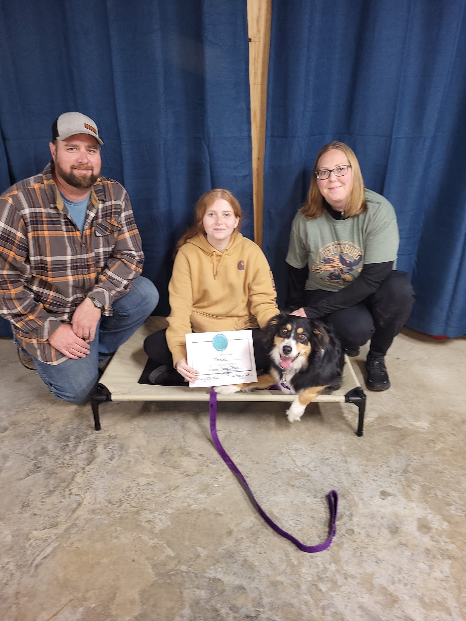 A family is posing for a picture with their dog