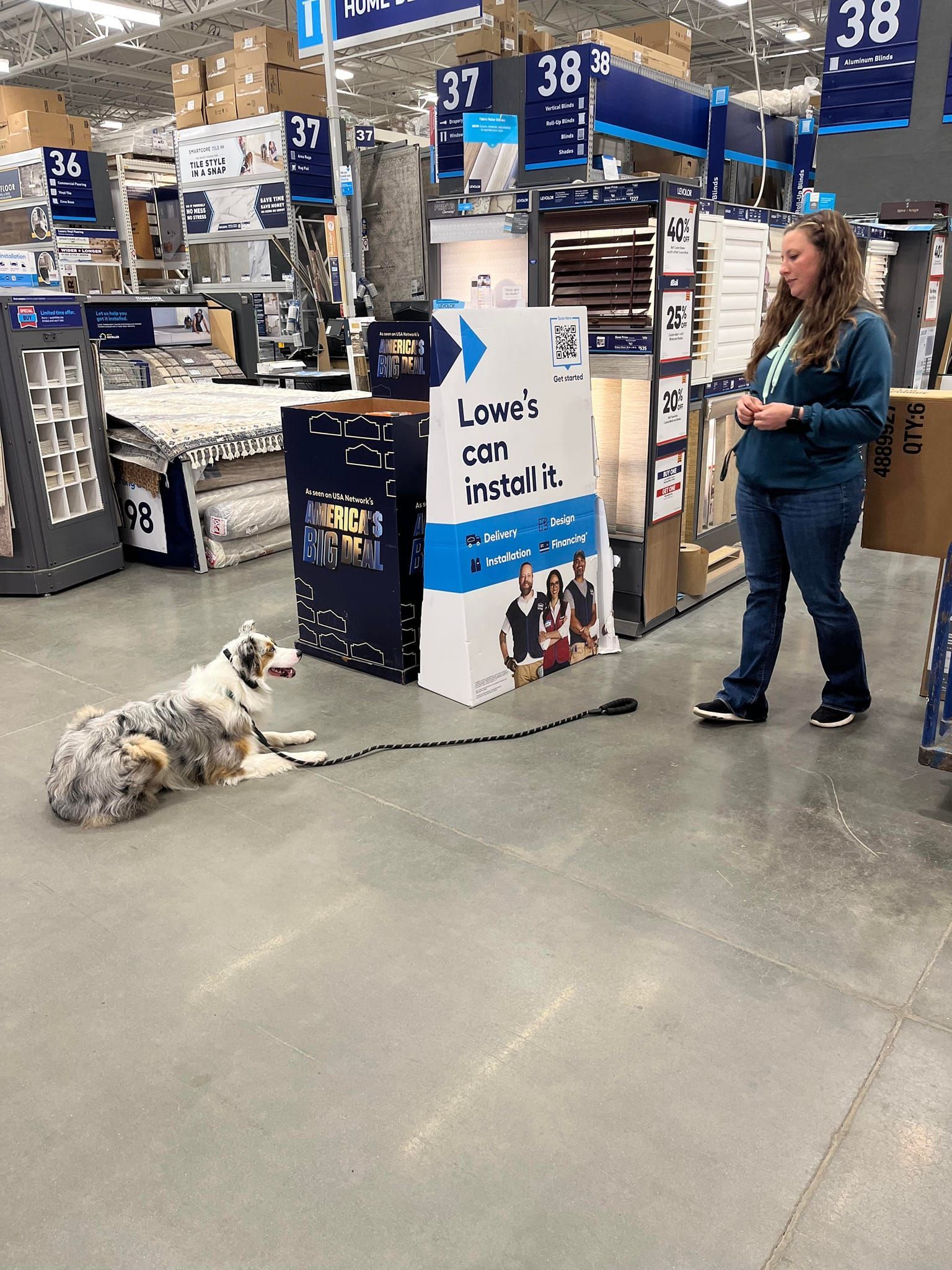 A woman is standing next to a dog on a leash in a store