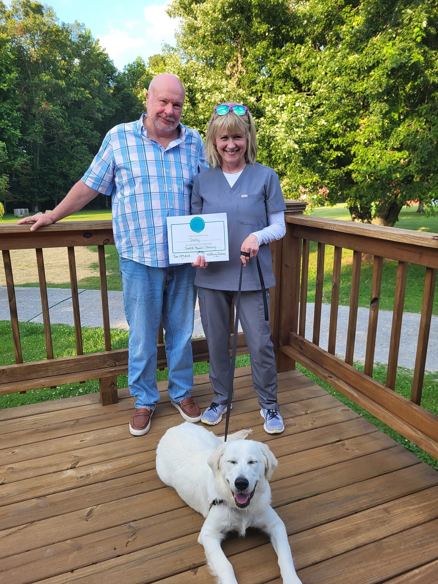 A man and a woman are standing on a deck with a dog