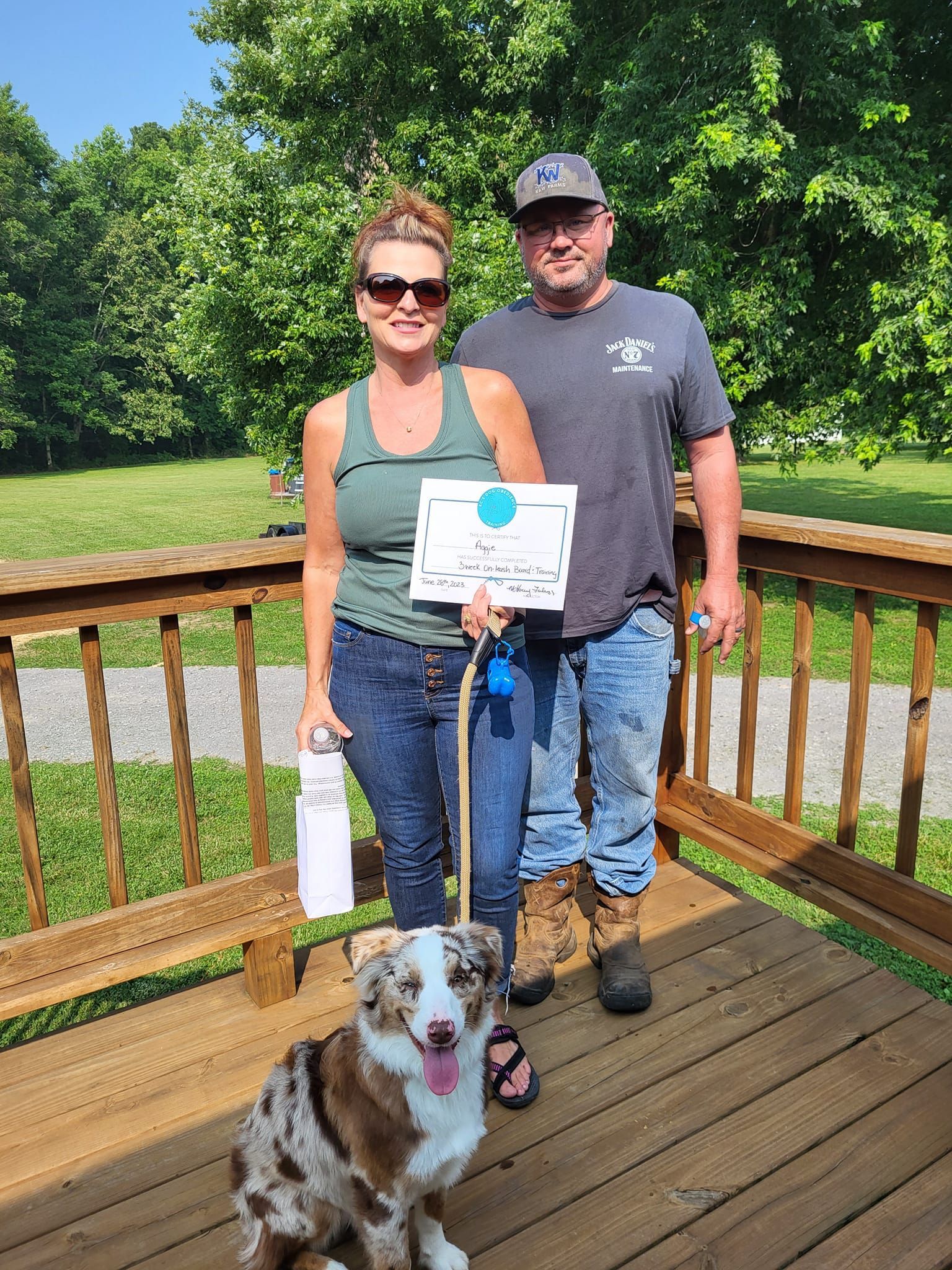 A man and a woman are standing on a deck with a dog