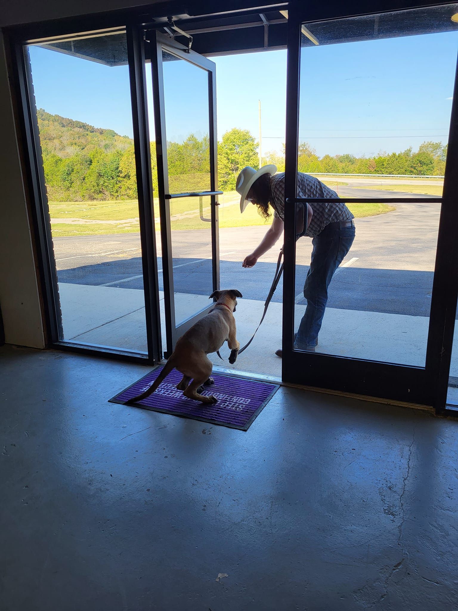 A woman is standing in a doorway with a dog on a leash