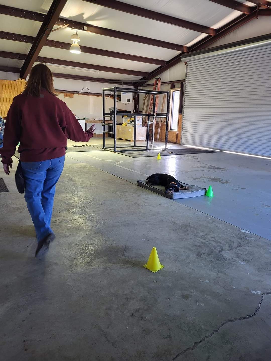 a woman is walking through a garage with cones on the floor
