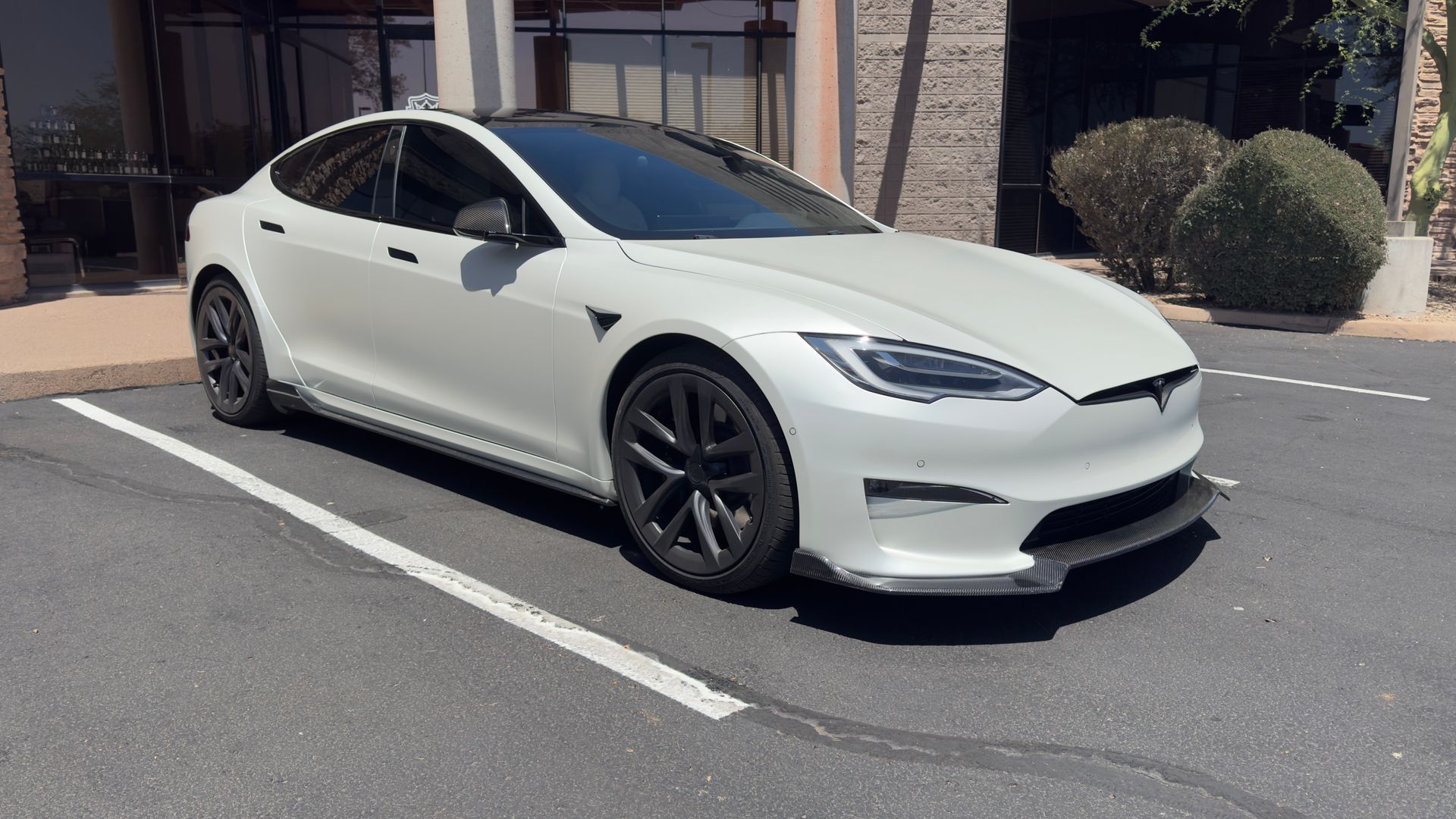 White Tesla sedan parked in a sunlit parking lot